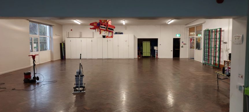 an assembly hall in a school having its hard floor cleaned